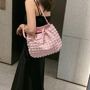 Pink bubble-textured tote bag with pearl chain detail worn by model for casual style