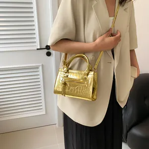 Detail of golden crocodile embossed handbag with rivet hardware and leather strap