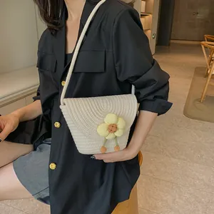 Detail of cream woven bucket bag with 3D yellow flower charm shown on model