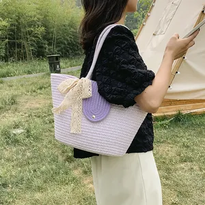 Detail of light purple woven tote bag with yellow lace bow and metal clasp closure