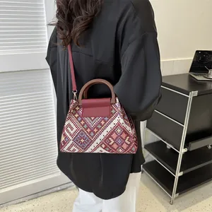 Detail of ethnic jacquard pattern crossbody bag with round wooden handle on a model