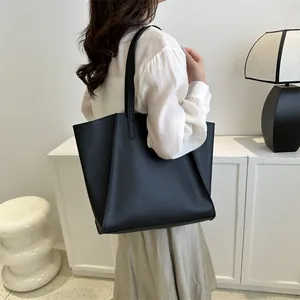 Bolso tote negro minimalista colocado sobre una mesa auxiliar en un interior moderno