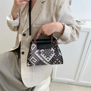 Detail of a vintage geometric woven crossbody bag with wooden handles and leather flap