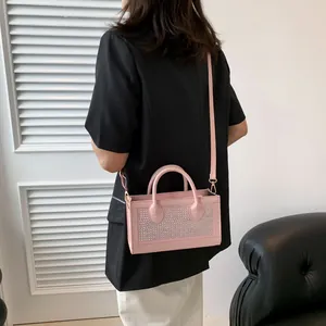 Pink rhinestone handbag with round handles and adjustable shoulder strap worn by a model