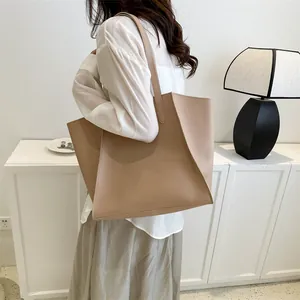 Detalle de un bolso tote grande de cuero caqui llevado por una modelo en un hogar acogedor