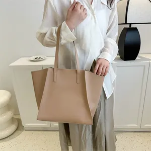 Detalle de un bolso tote beige minimalista con correas delgadas y estructura de trapecio