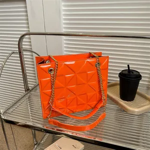 Détail du sac en cuir verni orange vif avec matelassage géométrique et chaîne dorée