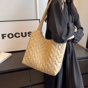Detail of beige quilted dumpling bag featuring 3D leaf texture and wide shoulder strap