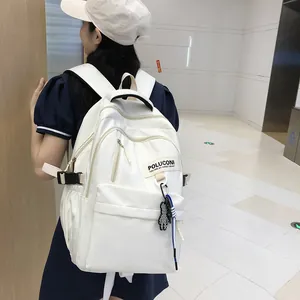 Détail d'un sac à dos blanc en nylon avec fermetures éclair et pendentif ours noir décoratif
