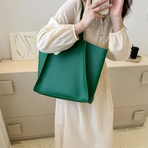 Detalle del bolso tote verde oscuro con pliegues laterales en cuero sintético mate suave