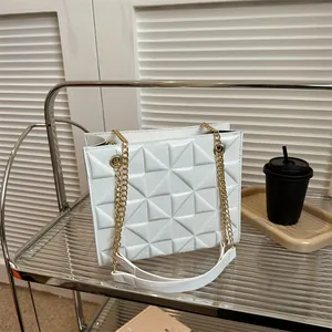 Détail d'un sac à main blanc matelassé avec motif géométrique et chaîne dorée