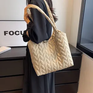 Detail of beige quilted tote bag with V-shape texture and wide shoulder strap