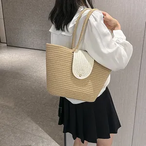 Detail of hand-woven straw tote bag with white contrast lid and golden buckle closure