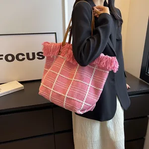 Détail d'un cabas en peluche à carreaux roses avec bordure à franges et anses marron