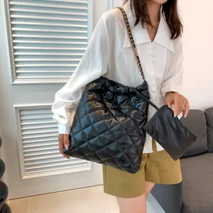 Detail of black quilted tote bag with chain strap and matching small zipper pouch