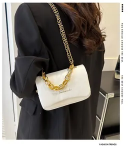 Détail du sac bandoulière en cuir blanc avec poignée en chaîne dorée et logo gravé