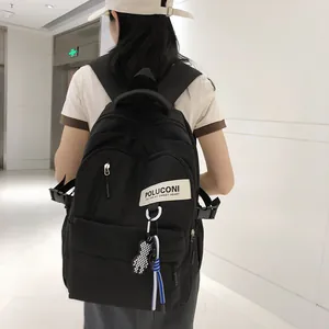 Gros plan d'un sac à dos noir minimaliste avec pendentif ours et écusson logo au dos