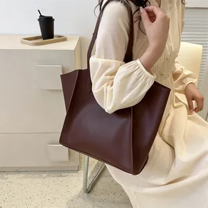 Detalle del bolso tote grande marrón oscuro de cuero con fuelles laterales en modelo