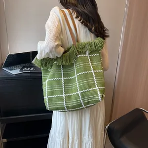 Détail du sac cabas tissé vert avec bordure à franges et poignées en cuir marron élégant