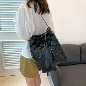 Close-up of black quilted tote bag with golden chain strap and matching zipper pouch