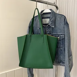 Detalle del bolso tote de cuero verde con diseño trapezoidal y pliegues laterales