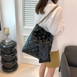 Detail of black quilted leather tote with metal chain strap and matching small pouch