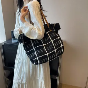 Détail du grand sac cabas à carreaux avec franges et anses en cuir marron pour voyage