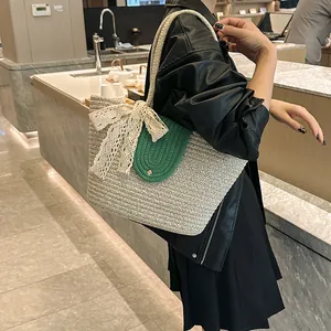 Detail of woven straw tote bag featuring a green knit flap and lace bow accent
