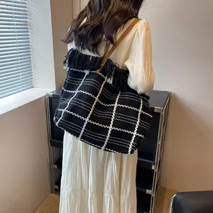 Détail du grand sac cabas tissé à carreaux avec franges noires et anse en cuir