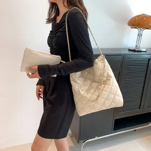 Fashionable beige quilted tote bag with golden chain strap shown on a model's shoulder