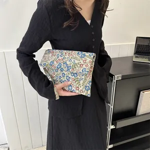 Detail of floral tapestry envelope clutch bag with vintage texture and flap closure