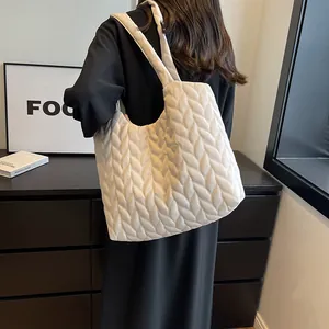 Quilted cream hobo bag with large capacity and soft pleated texture shown on shoulder