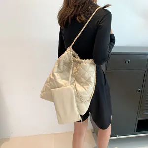 Fashionable beige quilted tote bag set with chain strap shown in a real-life carrying style