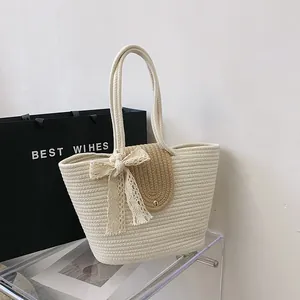 Detail of woven straw tote bag featuring a lace bow and brown leather magnetic flap