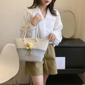 Détail d'un sac seau tissé avec un charm de tournesol jaune et des poignées en corde