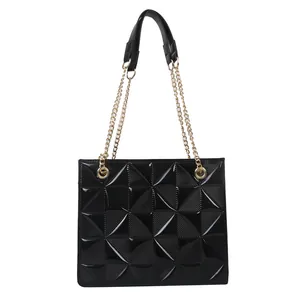 Sac fourre-tout noir matelassé géométrique avec chaîne dorée sur fond blanc impeccable