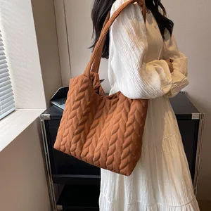 Caramel quilted tote bag with leaf pattern stitching worn as a crossbody bag for women