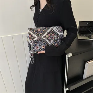 Close-up of geometric woven envelope clutch with gold floral clasp and wrist strap