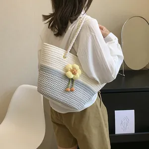 Détail du sac seau en corde tissée avec coutures bleu et blanc et fleur jaune