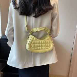 Modella che indossa una borsa a mezzaluna gialla trapuntata con tracolla regolabile