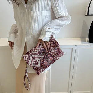 Detail of bohemian geometric pattern on vintage envelope clutch with clover charm