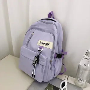 Détail d'un sac à dos en nylon violet clair avec étiquette et pendentif damier