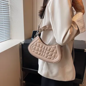 Vista laterale della borsa a spalla trapuntata beige con tracolla a pieghe e dettagli argento