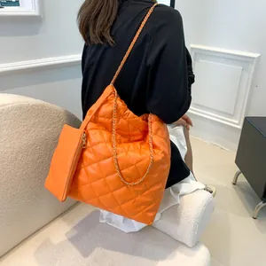 Detail of orange quilted tote bag with golden chain strap and matching small pouch
