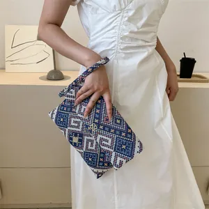 Detail of blue geometric tribal clutch featuring a gold clover buckle and wrist strap