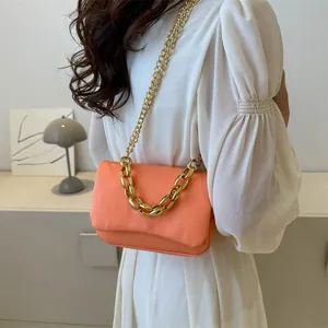Détail du sac à rabat orange corail avec grosse chaîne dorée et similicuir texturé