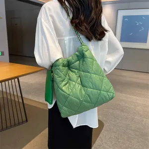 Detail of green quilted puffer tote bag featuring chain strap and matching coin purse