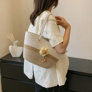 Détail du sac tissé avec poignées en corde et pendentif fleur en tricot décoratif