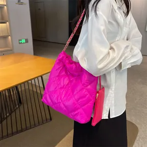 Detail of bright pink quilted tote bag with golden chain strap and mini coin purse