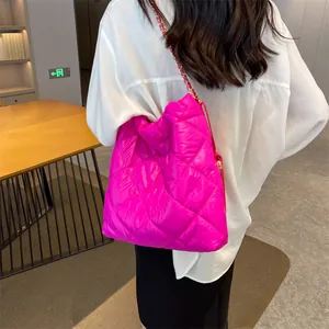 Detailed view of pink quilted tote bag with gold metal chain strap on model shoulder